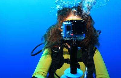 Giovane subacquea con una action cam durante un'immersione, mentre punta la fotocamera frontalmente.