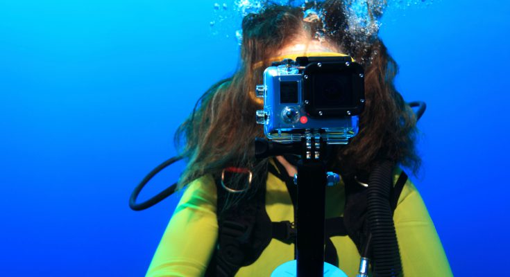 Giovane subacquea con una action cam durante un'immersione, mentre punta la fotocamera frontalmente.