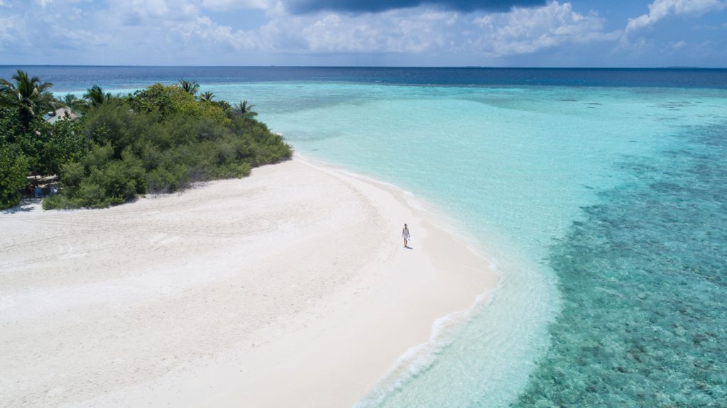 Isola delle Maldive con spiaggia bianca, reef e laguna turchese ripresi da drone