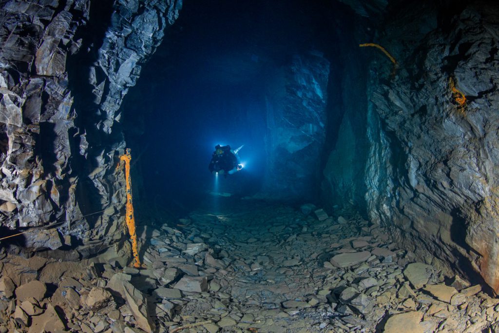 Vecchio carrello da miniera sulle rotaie nella miniera di ardesia allagata di Nuttlar durante un’immersione