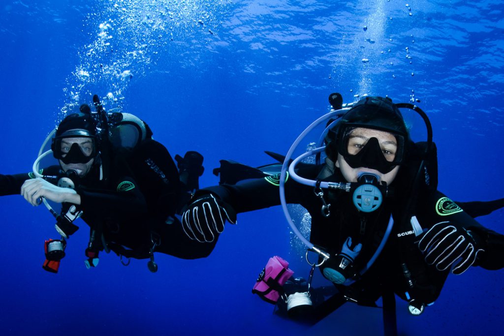 Due subacquei in coppia mentre esplorano le profondità marine in acque cristalline.