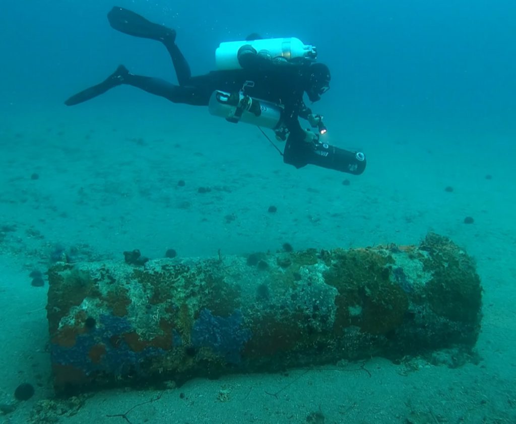 Subacqueo con DPV ispeziona un galleggiante in acciaio del reticolato parasommergibili della seconda guerra mondiale a Punta Sardegna