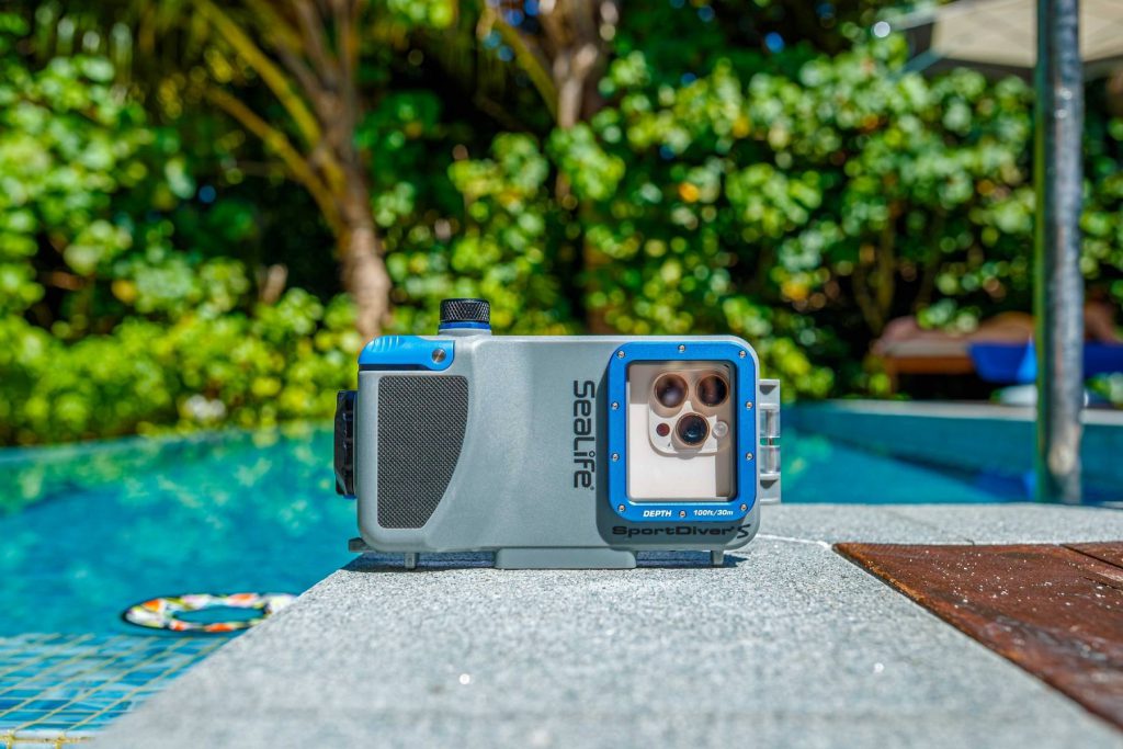 Custodia subacquea Sealife SportDiver S appoggiata a bordo piscina, con dettaglio del design compatto e della struttura rinforzata.