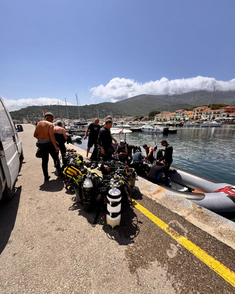 Attrezzatura subacquea disposta sul molo con i sub in preparazione per l'immersione