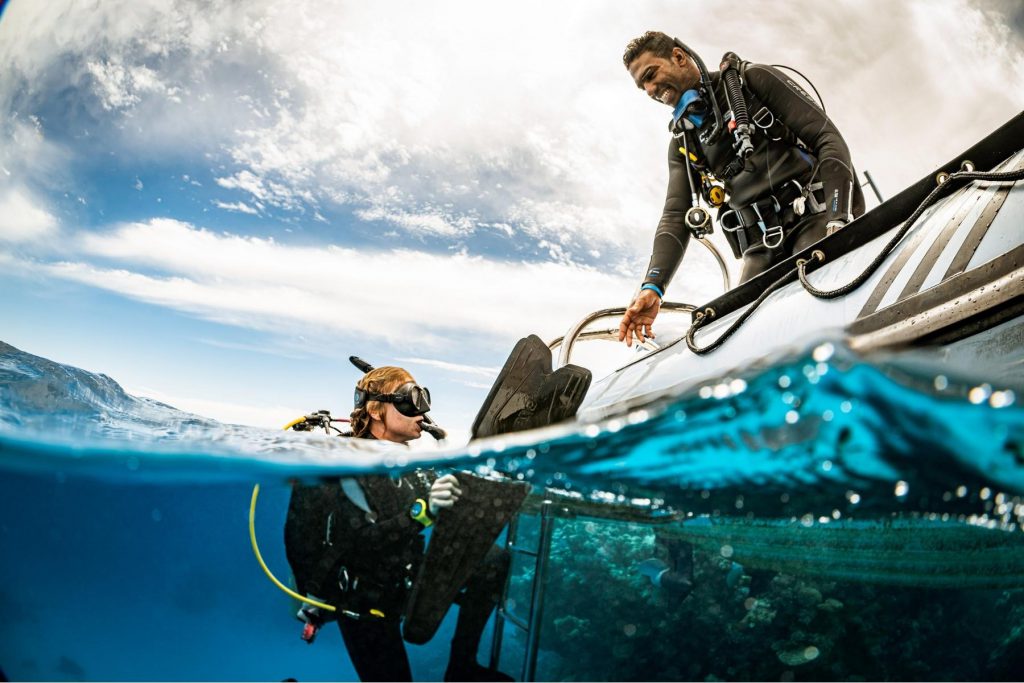 Subacqueo in risalita assistito da un istruttore PADI sulla barca, dopo un’immersione in acque tropicali.
