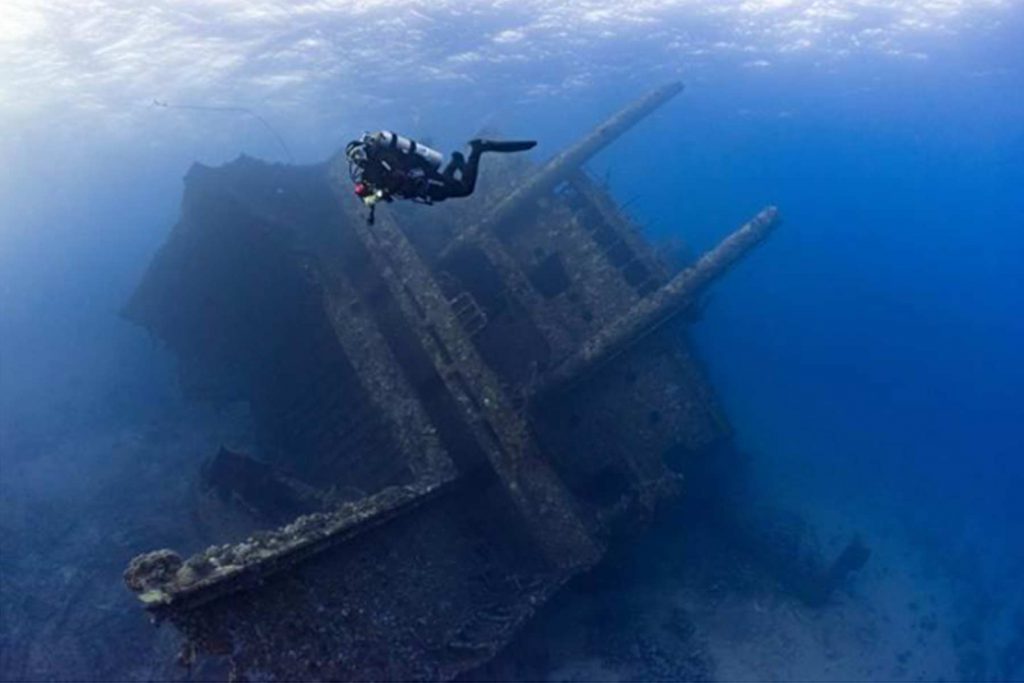 Un subacqueo che esplora un grande relitto sottomarino sommerso nelle acque italiane.