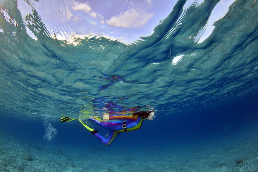 Persona in snorkeling vista dal basso sotto la superficie, in acque limpide e calme
