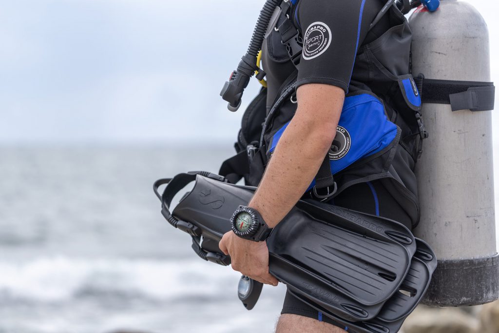 Subacqueo fuori dall'acqua con in mano pinne Scubapro Sistema modulare MFS di colore nero.