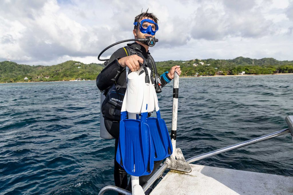 Subacqueo fuori dall'acqua con in mano pinne Scubapro Sistema modulare MFS di colore bianco+blu.