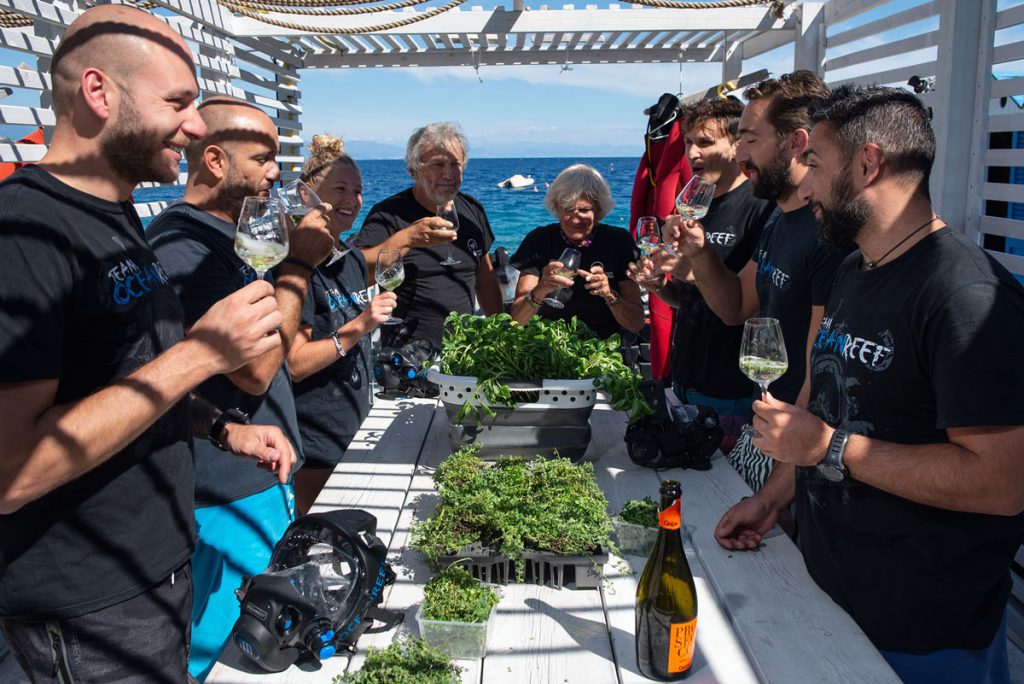 Il team del Giardino di Nemo brinda e degusta erbe aromatiche coltivate nelle serre subacquee, a bordo della struttura in mare.